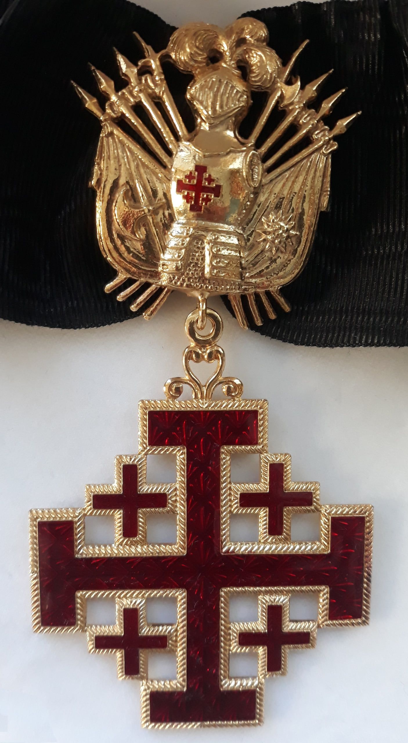 Însemnul de gât al Ordinului: crucea de Ierusalim smălțuită în roșu, surmontată de trofeul militar