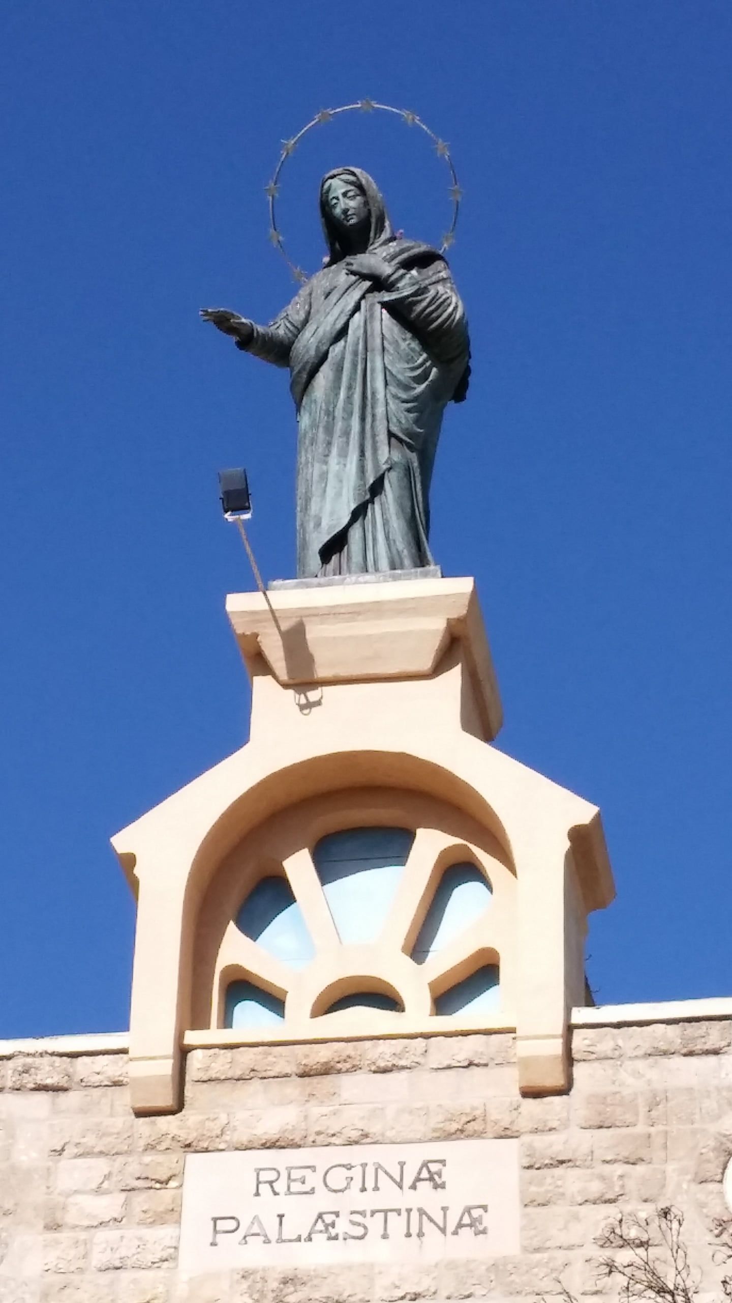 Statuia de bronz a Reginei Palestinei pe fațada sanctuarului de la Deir Rafat