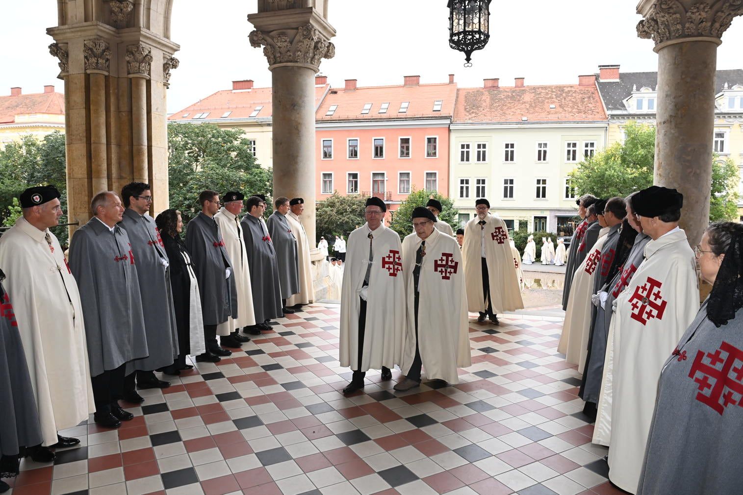 Cavaleri în mantii albe și doamne în mantii negre sub porticul unei biserici din Graz, 2023