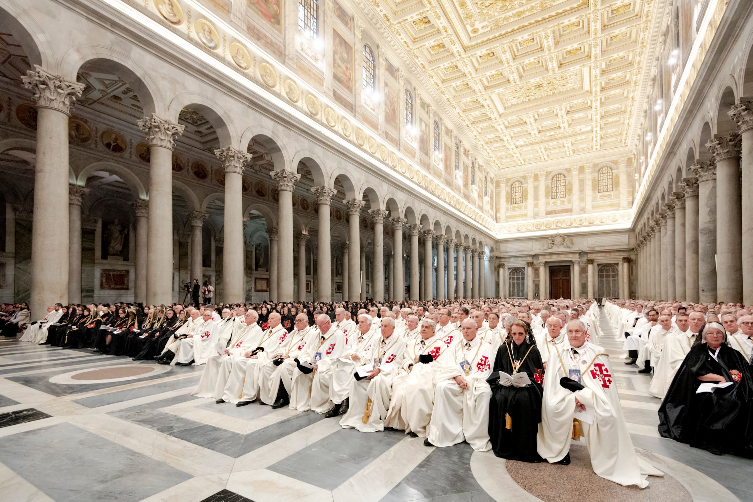 Cavaleri în mantii albe și doamne în mantii negre în nava Bazilicii Sfântul Paul din afara Zidurilor, la Roma