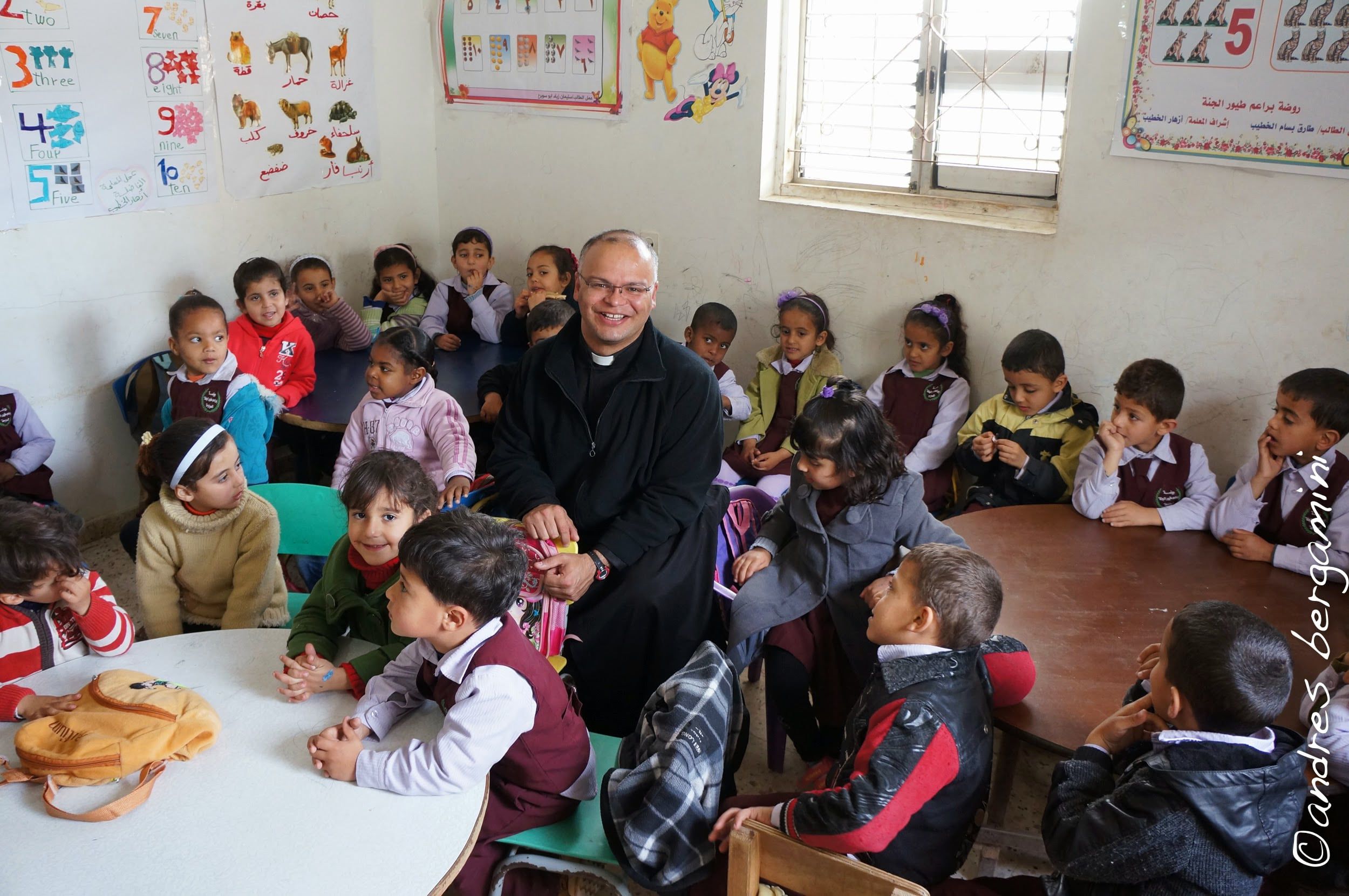 Copii într-o clasă a unei școli a Patriarhiei Latine, cu un preot